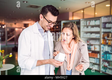 Il farmacista maschio che serve una femmina di cliente. Foto Stock