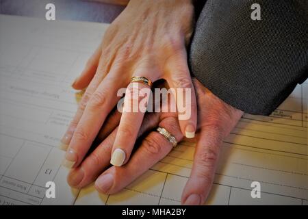 Una coppia di sposini che espongono la loro gli anelli di nozze prima di firmare il registro di matrimonio. Foto Stock