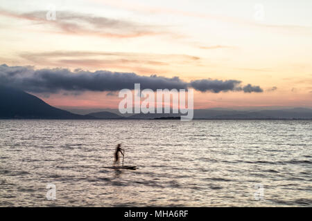 Silhouette di donna su uno stand up paddle board a Ribeirao da Ilha spiaggia al tramonto. Florianopolis, Santa Catarina, Brasile. Foto Stock