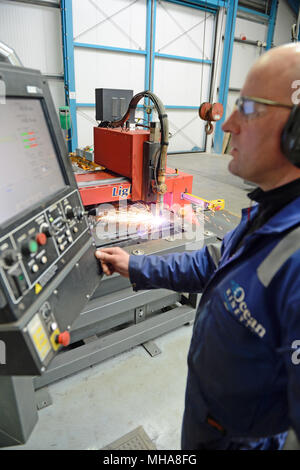 Uomo al lavoro su un metallo di plasma macchina di taglio in un'officina meccanica Foto Stock