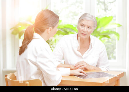 Persone di mezza età medico di radiologia nel suo ufficio che mostra il suo anziano paziente femmina l'ultima scansione ct del suo cervello Foto Stock