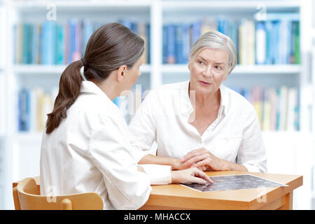 Medio di sesso femminile di età compresa tra medico nel suo intervento chirurgico che mostra la sua corsa senior paziente l'ultima scansione ct del suo cervello Foto Stock