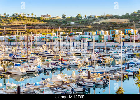 Molte barche a vela e barche a motore in marina con colorata architettura, Albufeira Algarve Foto Stock