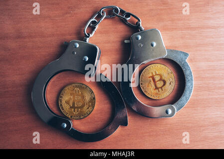 Le manette e bitcoins, immagine concettuale per cryptocurrency correlati arresto di polizia Foto Stock