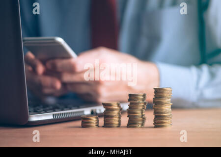 Costruzione di risparmio e aumento dei fondi di emergenza, imprenditore con impilati monete denaro sulla scrivania in ufficio Foto Stock