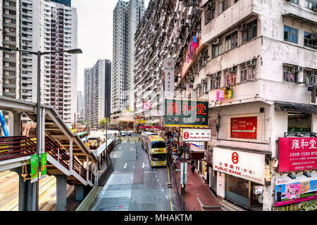 Servizio lavanderia appeso fuori ad asciugare dalle finestre di alto edificio di appartamenti in King's Road, Quarry Bay, Hong Kong Island. Di seguito, il traffico e gli acquirenti si mescolano. Foto Stock