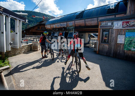 Gli amanti della mountain bike attendere per ottenere su Le Pleney skilift francesi nella città alpina di Morzine in estate. Foto Stock