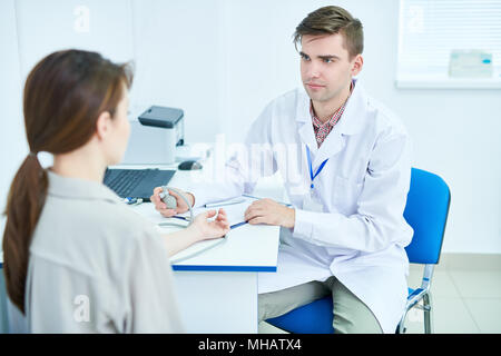 Ritratto di giovane medico la misura della pressione del sangue mediante tonometro in ufficio, spazio di copia Foto Stock
