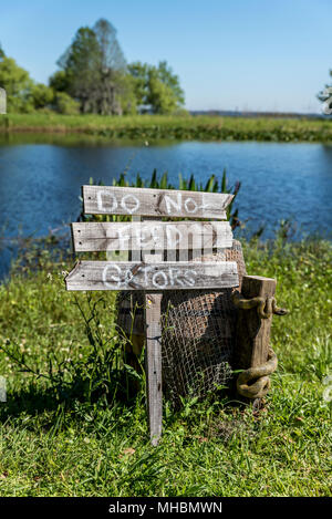 'Non alimentare che Gators" cartello in legno post, accanto a un lago nel sud profondo americano Foto Stock