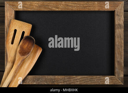 Cucina in legno utensili di cottura sul menu vuoto bordo con copia spazio su sfondo di legno Foto Stock