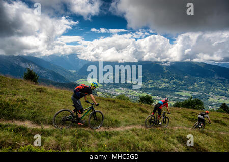 Un gruppo di uomini in mountain bike cavalcare un sentiero lungo una cresta vicino al Col de Joux piano nella direzione del francese città alpina di Samoëns. Foto Stock