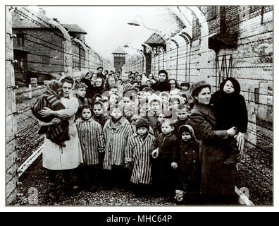 AUSCHWITZ BAMBINI SOPRAVVISSUTI DETENUTI NEONATI E DONNE UNIFORMI DA CAMPO A STRISCE LIBERAZIONE chiusa da tratti di filo spinato elettrificato e posti di guardia, che fissano senza emozione i loro liberatori. Un'altra cornice di orrore dal campo di concentramento nazista di Auschwitz Birkenau. Data di liberazione: Gennaio 27 1945. Foto Stock