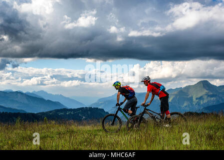 Due uomini ride mountain bike lungo una cresta vicino al francese località alpina di Morzine. Foto Stock
