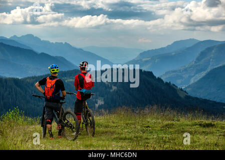 Due uomo su mountain bike stop per ammirare la vista accanto al francese città alpina di Morzine. Foto Stock