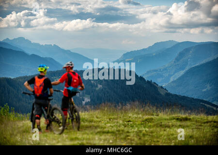 Due uomo su mountain bike stop per ammirare la vista accanto al francese città alpina di Morzine. Foto Stock