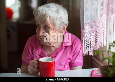 Donna anziana con la tazza di tè in cucina. Foto Stock