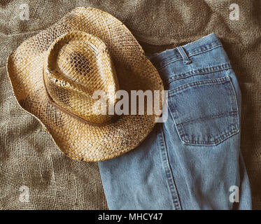 Cappello di paglia e sbiadita jeans blu su tela. Vista dall'alto in basso. Foto Stock