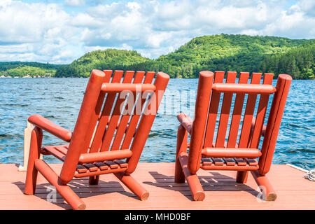 La vacanza estiva al lago, sedie di legno sull'estremità di un molo di legno su una visione idilliaca. Foto Stock