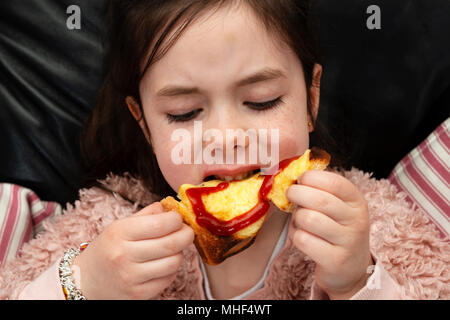 6 anno vecchia ragazza mangiare formaggio su pane tostato Foto Stock