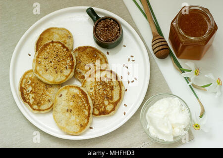 Frittelle di biancheria servito con il miele e la crema di formaggio su uno sfondo luminoso. Stile rustico. Foto Stock