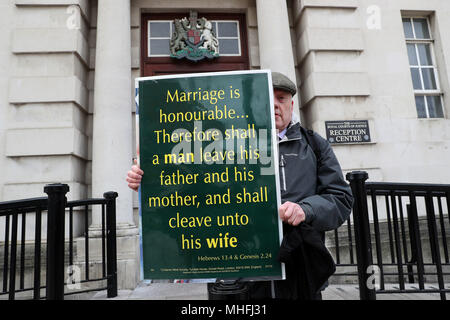 Un uomo detiene una targhetta citando la Bibbia al di fuori della Royal Courts of Justice a Belfast dove la Corte suprema sta esaminando le questioni legate al Ashers Baking Company "gay torta" caso. Picture Data: martedì 1 maggio 2018. Vedere PA storia ULSTER torta. Foto di credito dovrebbe leggere: Brian Lawless/PA FILO Foto Stock