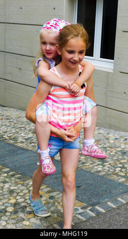 I bambini dando piggyback, piggy back bambino sorella portante sulla sua schiena, divertimento per tutta la famiglia Foto Stock