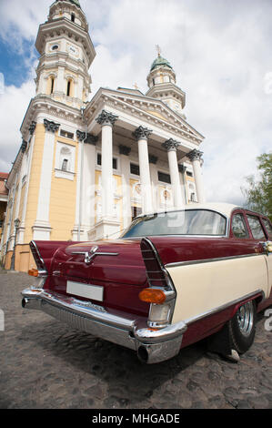 Uzhgorod, Ucraina - 18 Aprile 2015: il vecchio retrocar permanente sulla chiesa sfondo. Auto è molto bella e accurata. La bellissima chiesa edificio architeckture. Foto Stock
