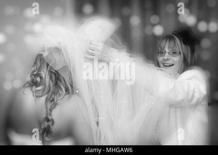 Madre aiutare sposa di vestire. Giorno di nozze preparato con la Madre e Sposa sorridente. Che fissa il velo su. Foto Stock