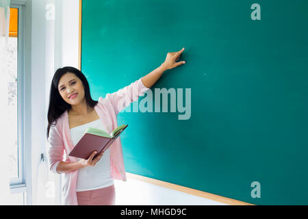 Ritratto di donna insegnante vicino a lavagna in aula Foto Stock