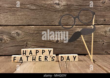 Felice giorno padri dei blocchi di legno con i baffi e occhiali contro un rustico sfondo di legno Foto Stock