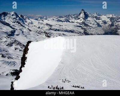 Molti paese indietro gli sciatori su un alto plateau sommitale nelle Alpi svizzere nei pressi di Zermatt con una fantastica vista del matterhorn dietro di loro Foto Stock