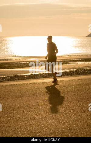 Il Galles, un freddo chiaro per iniziare la giornata per molti oggi con temperature appena sopra lo zero in parti del Galles del Nord. Alba sul Mare d'Irlanda e la passeggiata lungomare a Llandudno come una persona che prende un inizio corsa mattutina lungo il lungomare il giorno di maggio, il Galles del Nord Foto Stock