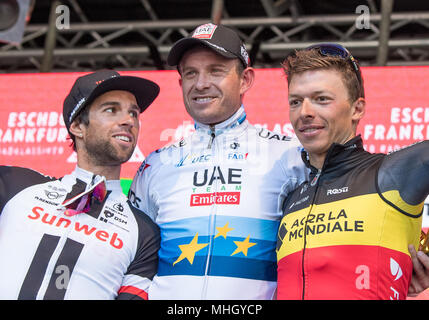 01 maggio 2018, Germania, Koenigstein-Mammolshain: il secondo posto Michael Matthews (da sinistra a destra) dall'Australia del team La Ragnatela Solare, vincitore Alexander Kristoff dalla Norvegia di Emirates Team e terzo posto Oliver Naesen dal Belgio di Team AG2R La Mondiale insieme in piedi sul podio durante la cerimonia di premiazione del Eschborn-Frankfurt cycling classic. Foto: Fabian Sommer/dpa Foto Stock