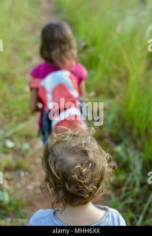 Due bambini di camminare su un sentiero di ghiaia in una foresta con illuminazione naturale, Mount Stuart sentieri escursionistici, Townsville, Queensland, Australia Foto Stock