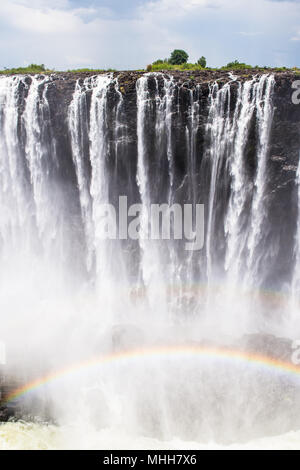 Rainbow su Victoria Falls, boarder dello Zambia e Zimbabwe. Patrimonio Mondiale UNESCO Foto Stock