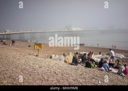Il molo vittoriano in Worthing West Sussex, in Inghilterra su un nebbioso giorno nel mese di aprile con i giovani sulla spiaggia Foto Stock