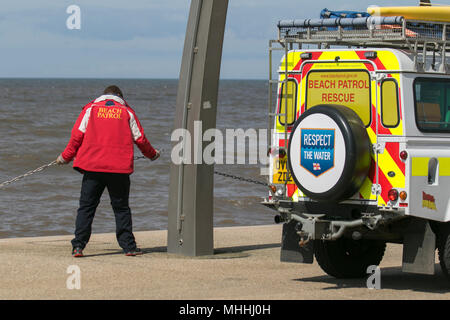 Spiaggia di salvataggio patrol Land Rover Veicolo con uomo che fissano lungomare delle catene per impedire accesso al mare.,Blackpool, Regno Unito Foto Stock