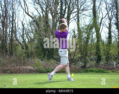 Giovane uomo di rinvio sul primo raccordo a T sul suo golf club locale, iniziando il suo percorso di golf. Foto Stock