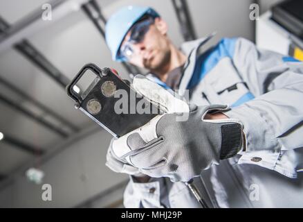 Per impieghi pesanti macchinari industriali operatore lavoratore con cavo remoto. Foto Stock