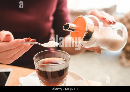 Femmina versa a mano per lo zucchero nel caffè caldo. Pranzo di lavoro Foto Stock