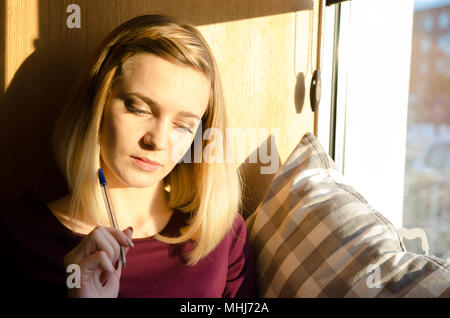 Bella ragazza pensieroso vicino alla finestra. Sunshiny ritratto Foto Stock