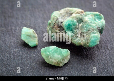 Materie emerald pietre preziose (minerale Berillo) con inclusioni estratta in Brasile su un grigio pietra ardesia Foto Stock