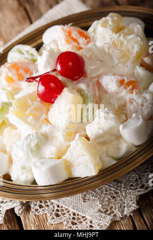 Insalata di frutta Ambrosia dal ananas, mandarino, uva e marshmelow close-up su una piastra verticale. Foto Stock