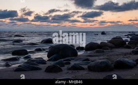 Un paesaggio marino all'alba con grandi pietre scure su una spiaggia deserta vicino Kaltene, Lettonia. Foto Stock