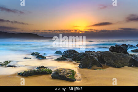 Fumoso Rocky Seascape - Catturare il sunrise da Killcare Beach sulla costa centrale, NSW, Australia. Foto Stock
