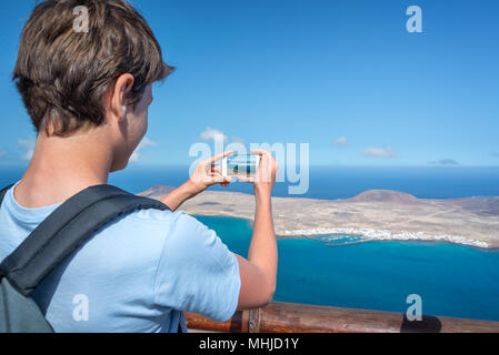 Giovane uomo di scattare le foto con il suo smartphone, in Lanzarote, Spagna Foto Stock