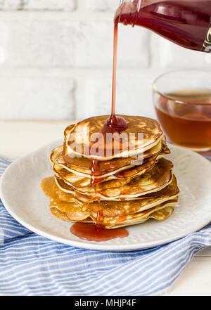 Pancake fatti in casa versato gocce di sciroppo in piastra bianca, primo piano Foto Stock