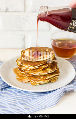 Pancake fatti in casa versato gocce di sciroppo in piastra bianca, primo piano Foto Stock