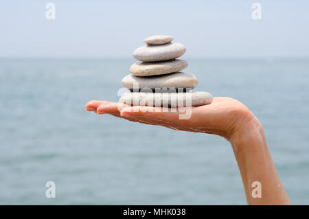 Close-up del mucchio di ghiaia nella donna le mani con lo sfondo del mare Foto Stock