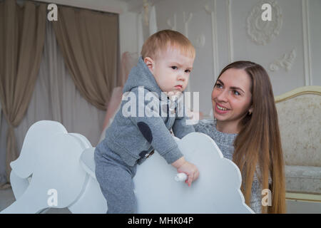 Little Boy giocando su legno cavallo a dondolo Foto Stock